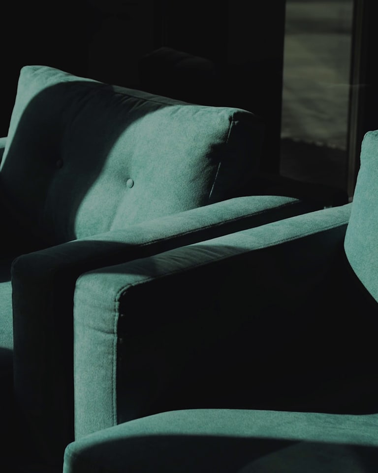 Two teal armchairs beside a window in soft natural light