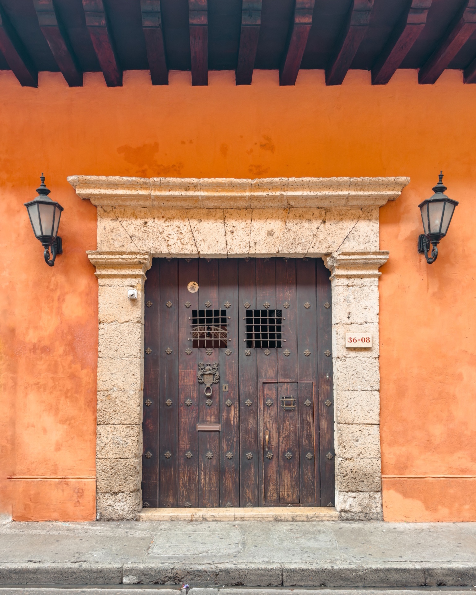 A dark wooden double door set in an orange colonial facade