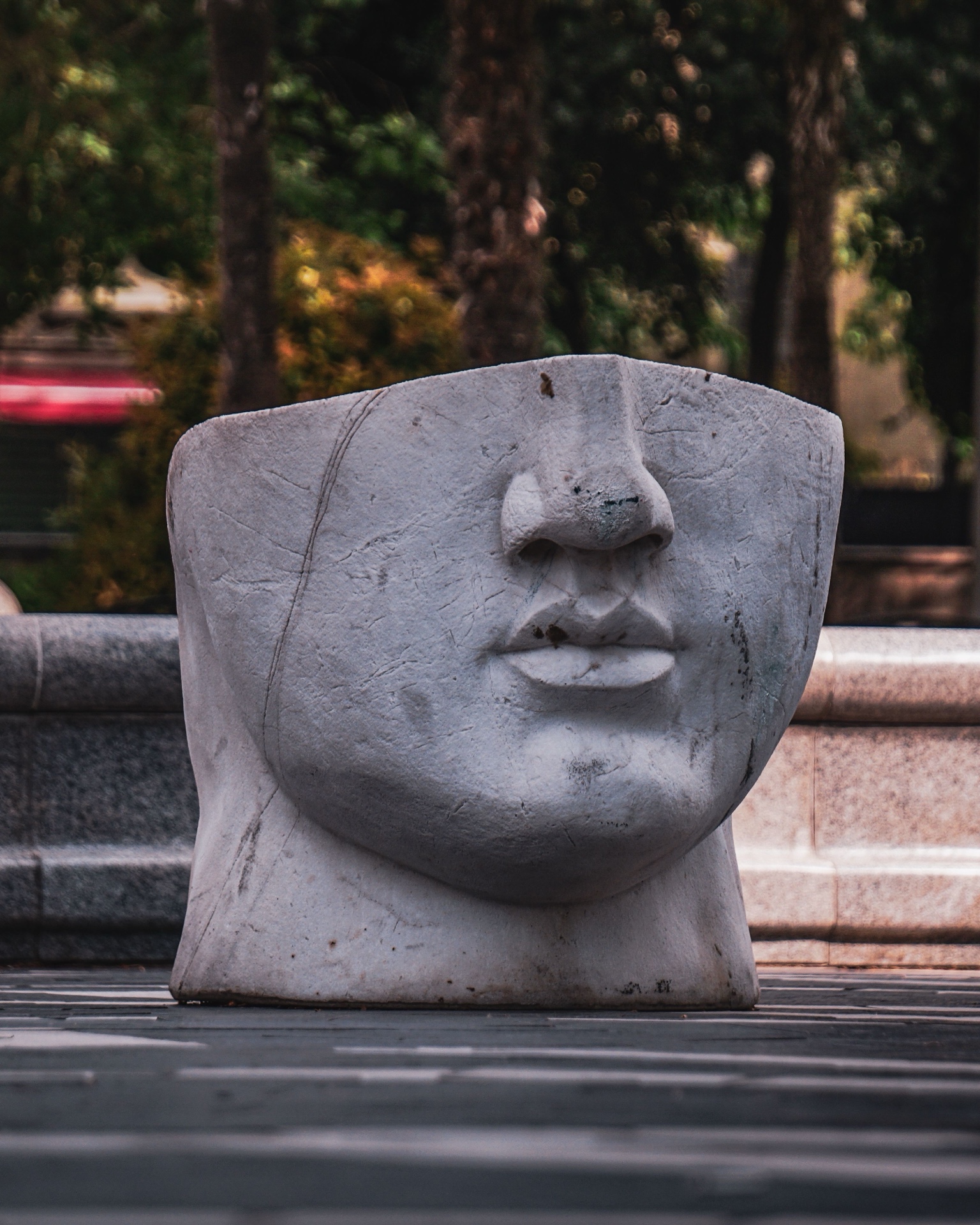 An abstract stone face sculpture in a park setting