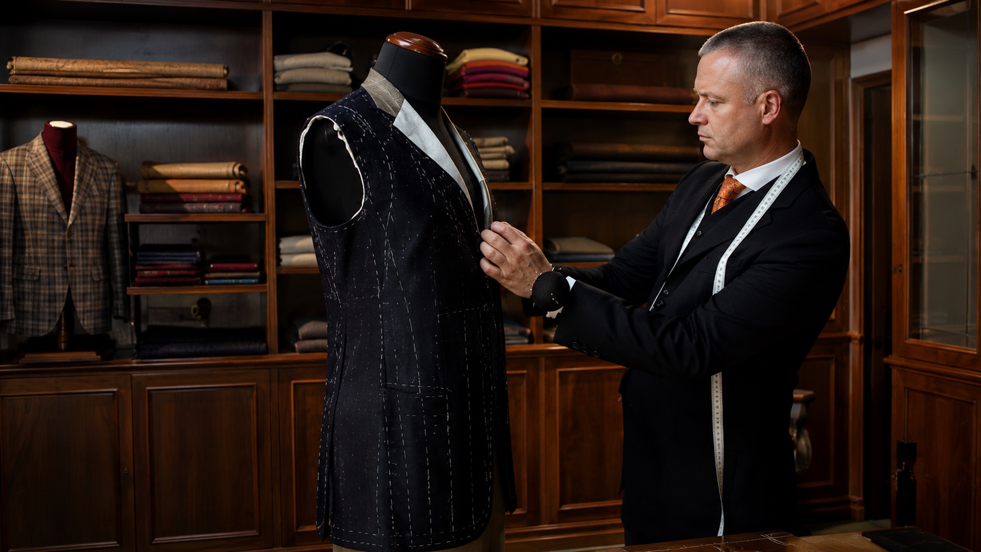 A tailor shaping a jacket by hand in a wood-panelled workroom