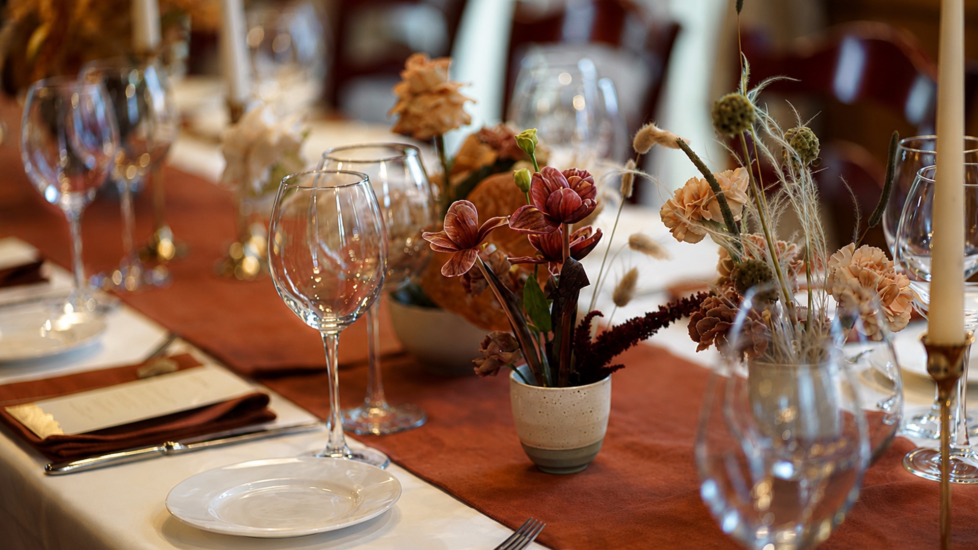 A long dinner table set with flowers and candlelight, the chairs still empty