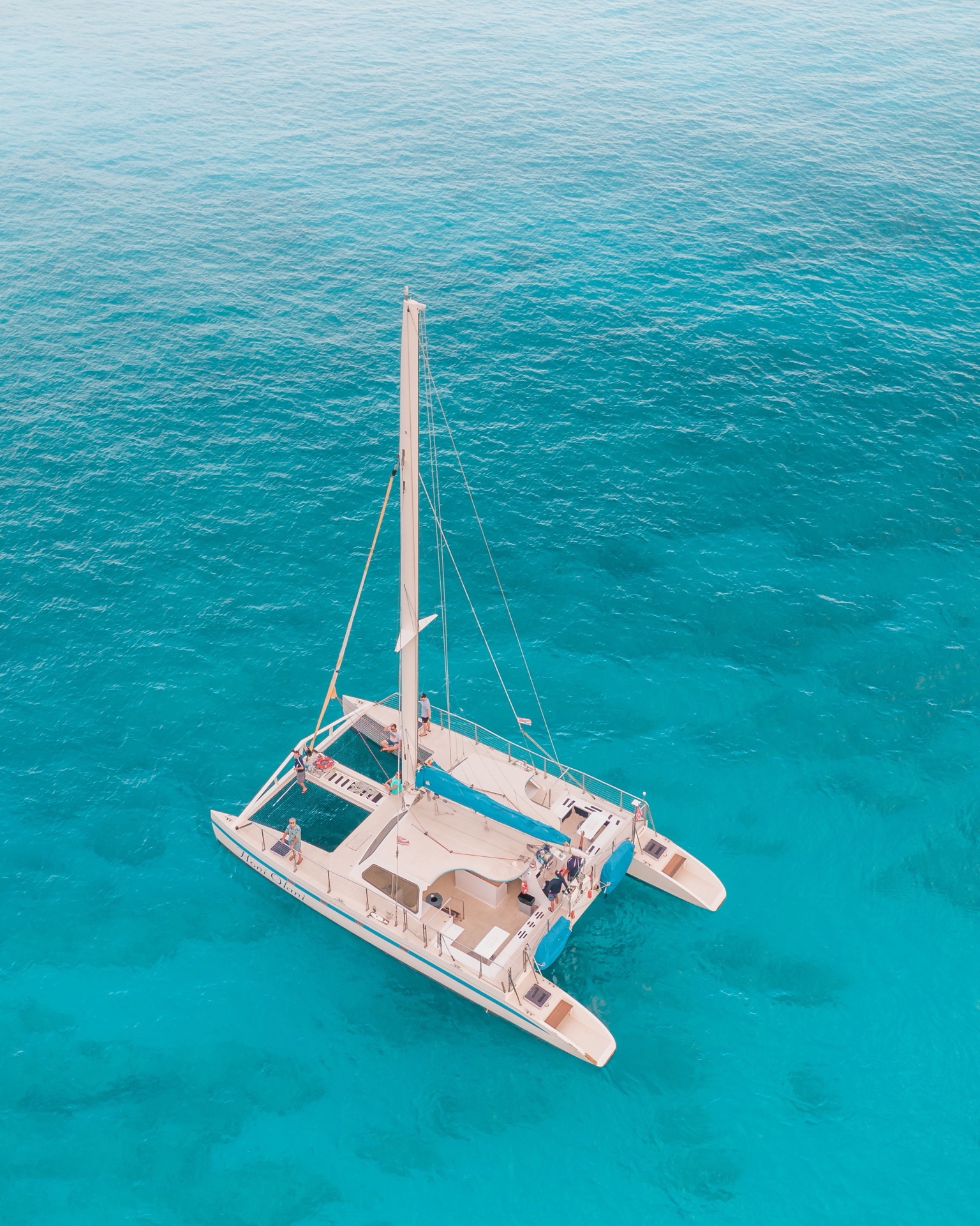 An aerial view of a catamaran anchored over turquoise water